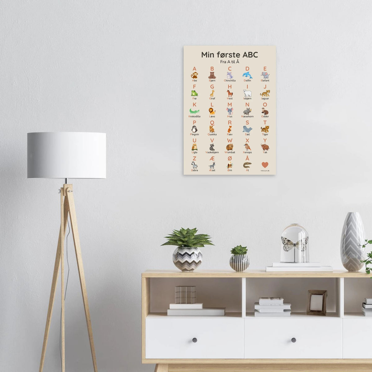 ABC-plakat stillet op ad væggen ved en reol med legetøj
